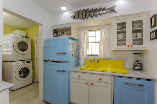 1523 22nd St, Galveston, TX 77550 - kitchen featuring freestanding refrigerator, stacked washer and clothes dryer, white cabinetry, glass insert cabinets, and backsplash