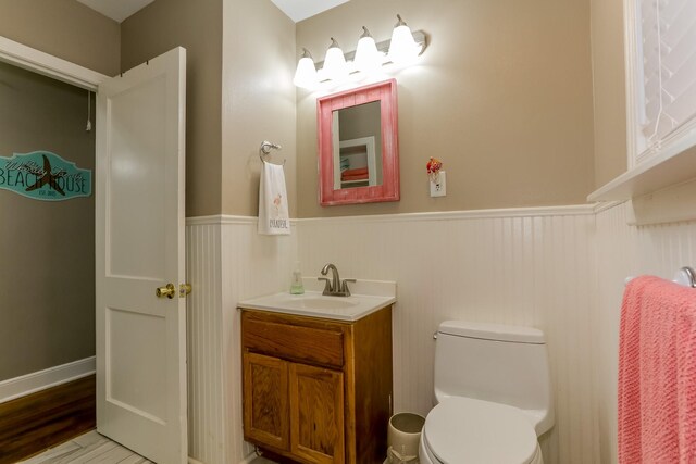 1523 22nd St, Galveston, TX 77550 - half bathroom with wainscoting, vanity, toilet, and wood finished floors
