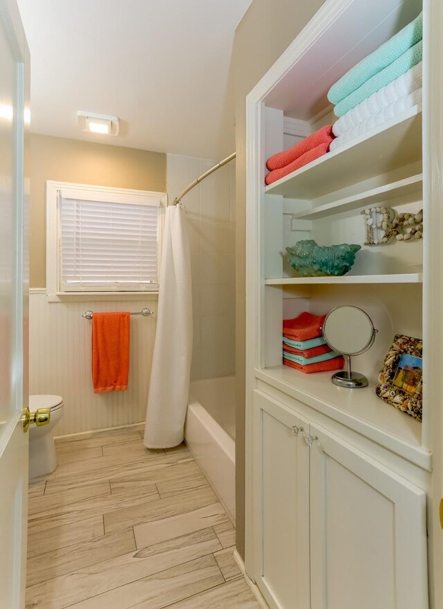 1523 22nd St, Galveston, TX 77550 - full bathroom featuring toilet, shower / tub combo, wood finished floors, and wainscoting