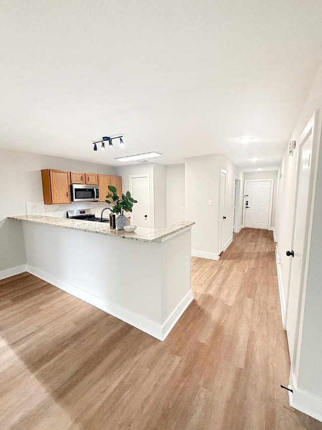 17422 Typhoon Way, Crosby, TX 77532 - kitchen featuring light wood-style floors, stainless steel microwave, a peninsula, and baseboards