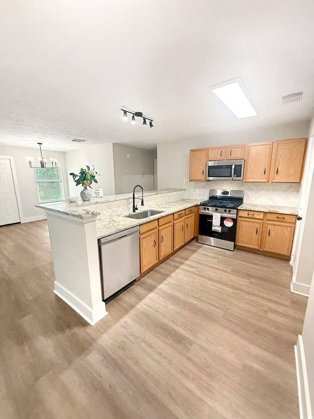 17422 Typhoon Way, Crosby, TX 77532 - kitchen featuring stainless steel appliances, a sink, a peninsula, light wood finished floors, and light stone counters