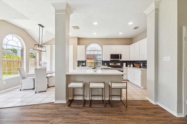 4643 Forest Home Dr, Missouri City, TX 77459 - kitchen with appliances with stainless steel finishes, backsplash, white cabinetry, a breakfast bar, and recessed lighting