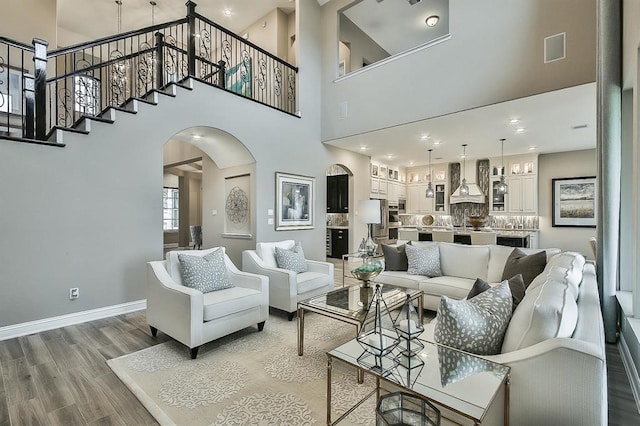 29506 Highland Manor Ct, Katy, TX 77494 - living room featuring arched walkways, a towering ceiling, light wood-type flooring, baseboards, and stairs