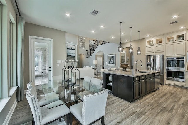 29506 Highland Manor Ct, Katy, TX 77494 - kitchen with arched walkways, stainless steel appliances, a sink, light wood-type flooring, and recessed lighting