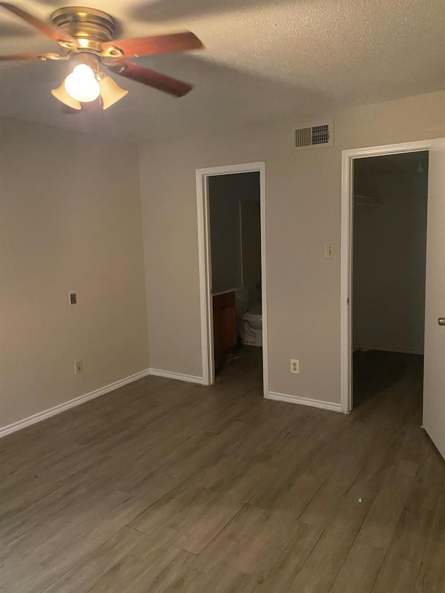 9797 Leawood Blvd Unit 408, Houston, TX 77099 - unfurnished bedroom with a spacious closet, dark wood-type flooring, baseboards, connected bathroom, and a textured ceiling
