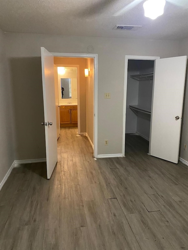 9797 Leawood Blvd Unit 408, Houston, TX 77099 - unfurnished bedroom featuring baseboards, wood finished floors, a walk in closet, and a closet
