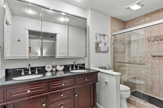 2505 Gerol Dr, Galveston, TX 77551 - full bathroom with a textured ceiling, toilet, double vanity, a shower stall, and tile patterned flooring