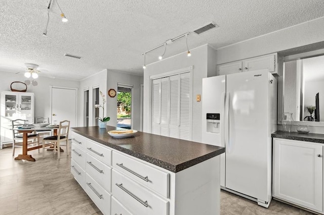 2505 Gerol Dr, Galveston, TX 77551 - kitchen featuring white refrigerator with ice dispenser, dark countertops, white cabinetry, a textured ceiling, and a ceiling fan