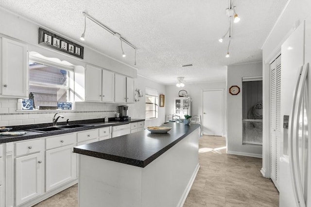 2505 Gerol Dr, Galveston, TX 77551 - kitchen with a sink, white refrigerator with ice dispenser, track lighting, white cabinets, and a textured ceiling