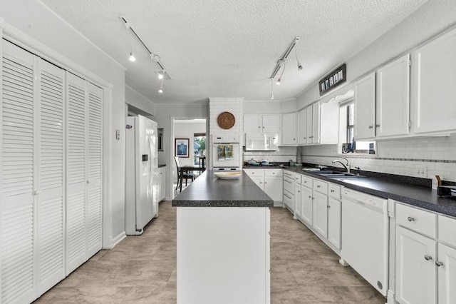 2505 Gerol Dr, Galveston, TX 77551 - kitchen featuring white appliances, track lighting, a sink, a kitchen island, and dark countertops