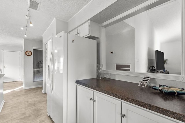 2505 Gerol Dr, Galveston, TX 77551 - kitchen featuring freestanding refrigerator, white cabinets, a textured ceiling, dark countertops, and track lighting