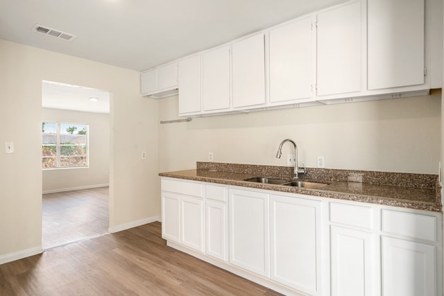 4726 Angleton St, Houston, TX 77033 - kitchen with a sink, light wood-style flooring, baseboards, and white cabinets