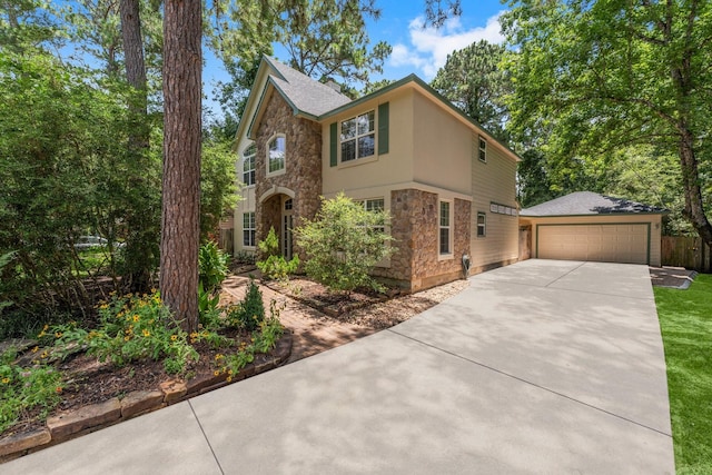 62 Treescape Cir, The Woodlands, TX 77381 - traditional-style home with stone siding, concrete driveway, and an outbuilding