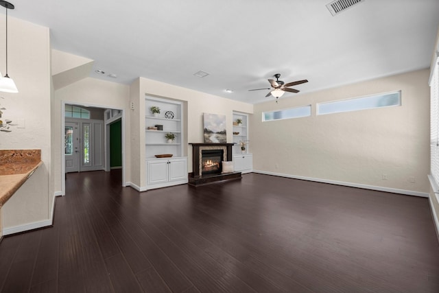 62 Treescape Cir, The Woodlands, TX 77381 - unfurnished living room featuring ceiling fan, built in shelves, baseboards, and dark wood-type flooring