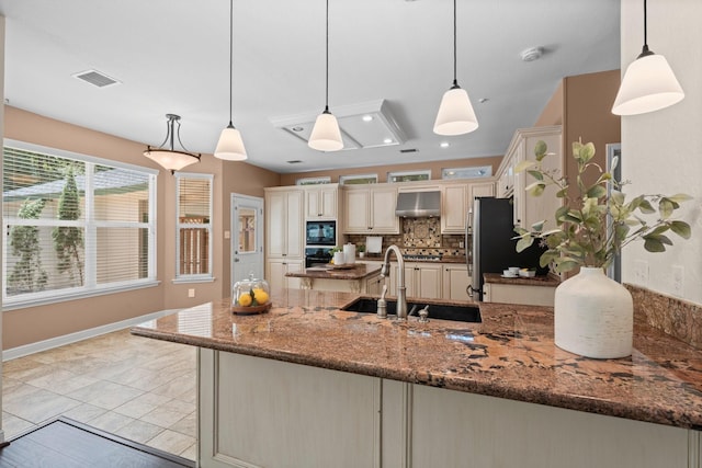 62 Treescape Cir, The Woodlands, TX 77381 - kitchen with wall chimney range hood, a sink, cream cabinetry, black appliances, and tasteful backsplash