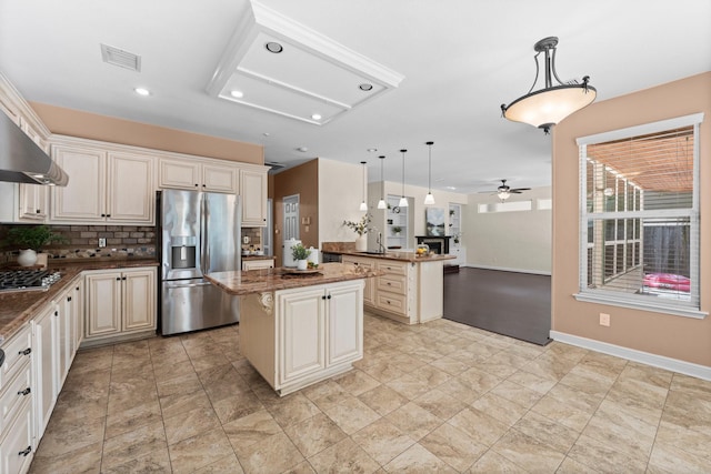 62 Treescape Cir, The Woodlands, TX 77381 - kitchen featuring appliances with stainless steel finishes, cream cabinetry, open floor plan, a ceiling fan, and backsplash