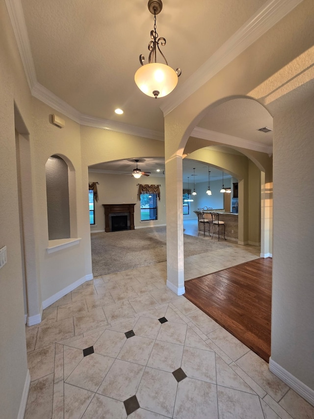 1008 Heritage Oaks Dr, Angleton, TX 77515 - foyer entrance featuring a fireplace, ornamental molding, ceiling fan, baseboards, and arched walkways