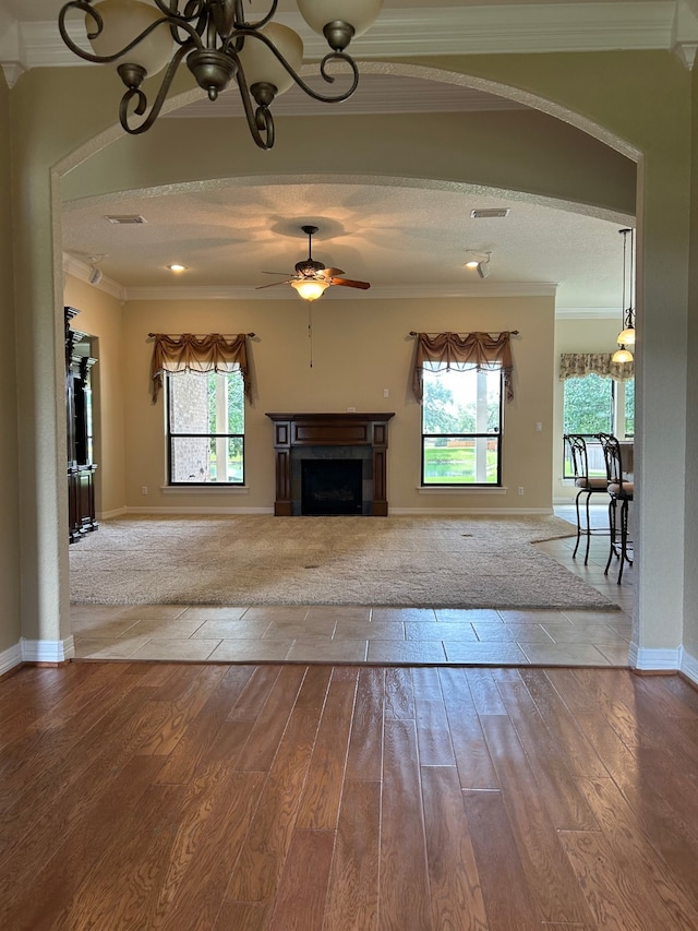1008 Heritage Oaks Dr, Angleton, TX 77515 - unfurnished living room featuring a ceiling fan, ornamental molding, arched walkways, a fireplace, and wood finished floors