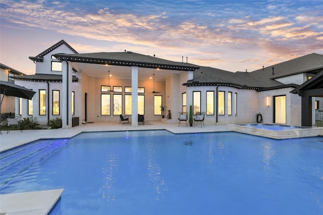 18115 Bachman Branch Dr, Cypress, TX 77433 - back of house at dusk with stucco siding, a patio area, and a pool with connected hot tub