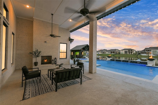 18115 Bachman Branch Dr, Cypress, TX 77433 - pool at dusk with a ceiling fan, an outdoor living space with a fireplace, a patio area, a residential view, and a pool with connected hot tub