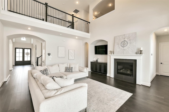 18115 Bachman Branch Dr, Cypress, TX 77433 - living area with dark wood-style floors, baseboards, arched walkways, a high ceiling, and a tiled fireplace