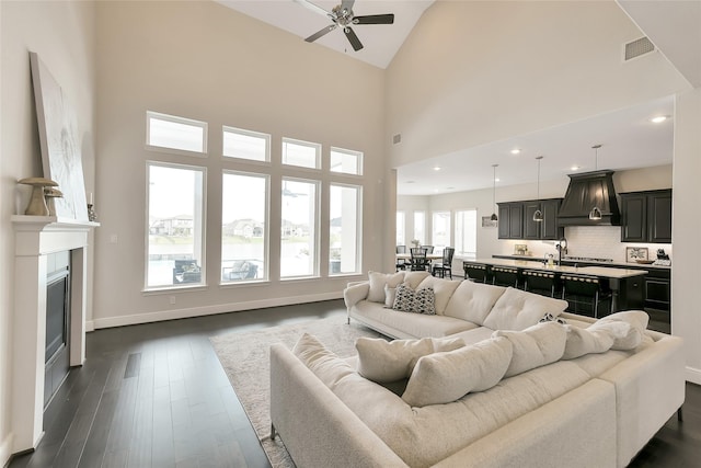18115 Bachman Branch Dr, Cypress, TX 77433 - living room featuring ceiling fan, dark wood finished floors, baseboards, high vaulted ceiling, and a glass covered fireplace