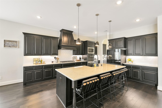 18115 Bachman Branch Dr, Cypress, TX 77433 - kitchen with appliances with stainless steel finishes, custom range hood, dark wood-style floors, a breakfast bar area, and recessed lighting