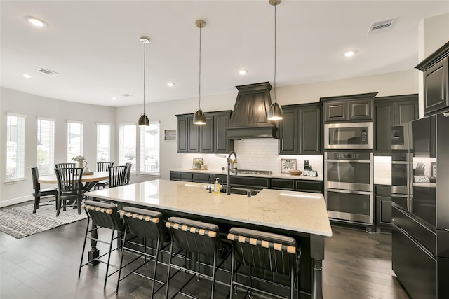 18115 Bachman Branch Dr, Cypress, TX 77433 - kitchen featuring appliances with stainless steel finishes, premium range hood, light stone countertops, backsplash, and dark wood-style flooring