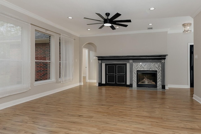 43 Danville Crossing Ct, The Woodlands, TX 77385 - unfurnished living room with light wood-style floors, arched walkways, a ceiling fan, a fireplace, and crown molding