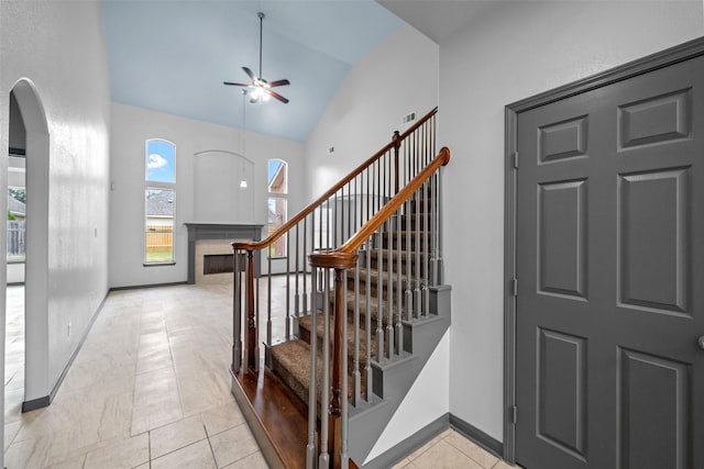 13909 Stonewood Ct, Rosharon, TX 77583 - stairway with a ceiling fan, arched walkways, baseboards, high vaulted ceiling, and tile patterned flooring
