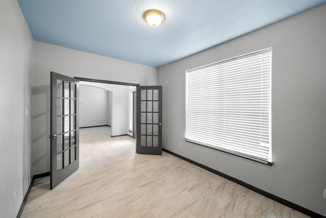 13909 Stonewood Ct, Rosharon, TX 77583 - spare room with french doors, baseboards, arched walkways, and a baseboard radiator