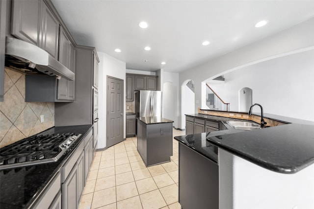 13909 Stonewood Ct, Rosharon, TX 77583 - kitchen featuring stainless steel appliances, arched walkways, ventilation hood, a kitchen island, and decorative backsplash