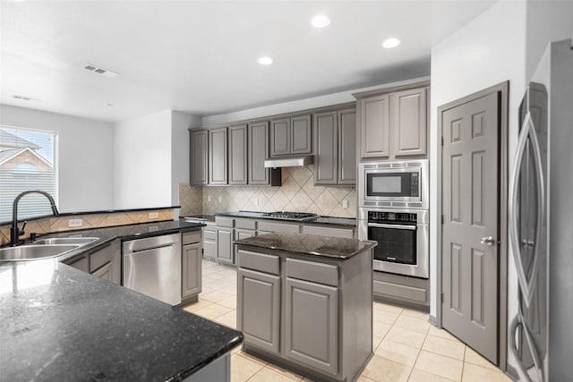 13909 Stonewood Ct, Rosharon, TX 77583 - kitchen featuring a sink, appliances with stainless steel finishes, a center island, decorative backsplash, and gray cabinets