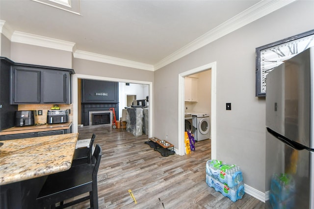 23214 Gatecreek Ct, Katy, TX 77494 - kitchen with freestanding refrigerator, independent washer and dryer, ornamental molding, light countertops, and light wood-style flooring