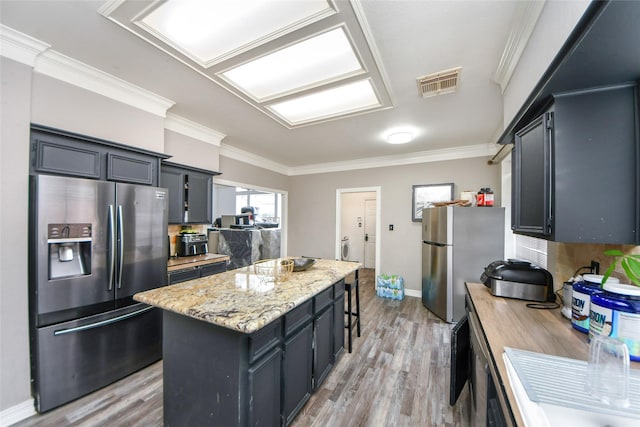 23214 Gatecreek Ct, Katy, TX 77494 - kitchen featuring stainless steel fridge with ice dispenser, freestanding refrigerator, a kitchen island, light wood-style floors, and ornamental molding