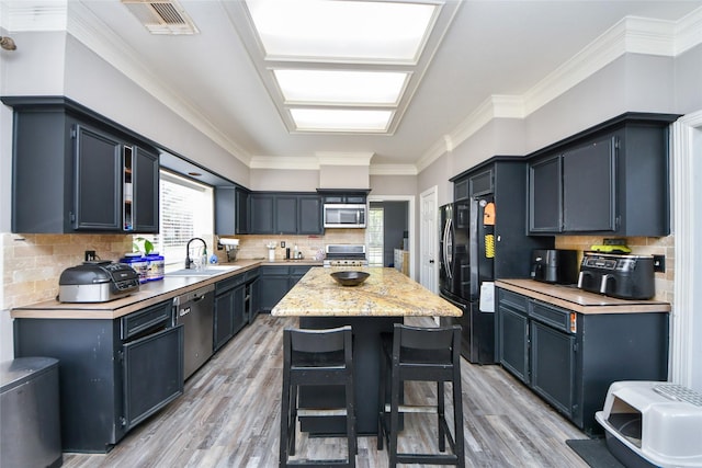 23214 Gatecreek Ct, Katy, TX 77494 - kitchen with appliances with stainless steel finishes, a sink, light wood-style flooring, a center island, and tasteful backsplash