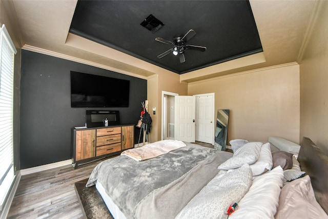 23214 Gatecreek Ct, Katy, TX 77494 - bedroom with a tray ceiling, wood finished floors, ornamental molding, multiple windows, and baseboards