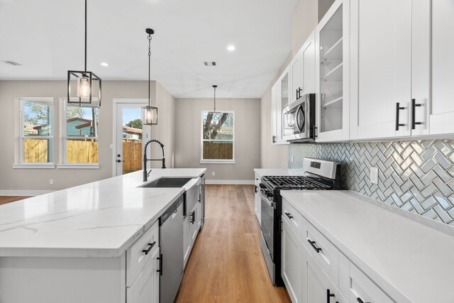 5833 Highland Sun Ln, Houston, TX 77091 - kitchen featuring appliances with stainless steel finishes, light wood finished floors, a sink, tasteful backsplash, and baseboards