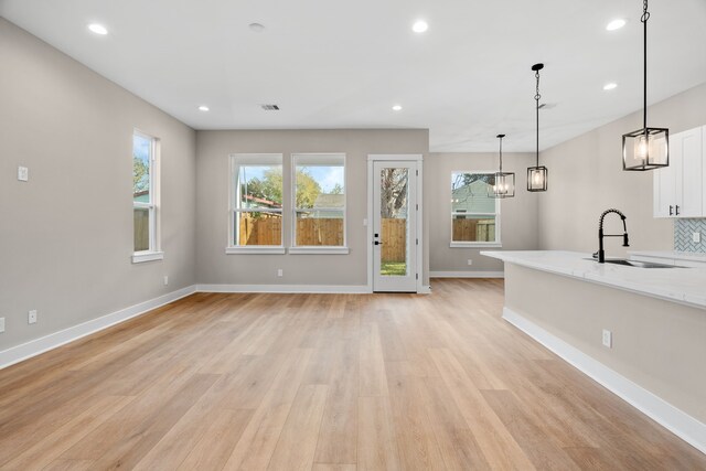5833 Highland Sun Ln, Houston, TX 77091 - unfurnished living room featuring a sink, light wood-style floors, baseboards, recessed lighting, and a chandelier