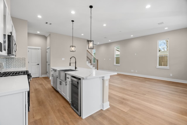 5833 Highland Sun Ln, Houston, TX 77091 - kitchen with wine cooler, a sink, appliances with stainless steel finishes, white cabinets, and recessed lighting