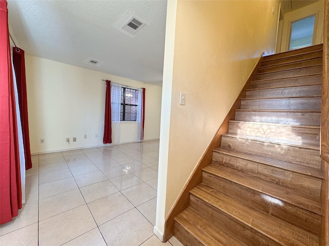 8631 Mapletwist St, Houston, TX 77083 - stairway featuring baseboards, tile patterned flooring, and a textured ceiling