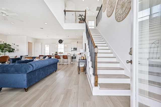 4101 5th St, Galveston, TX 77554 - living room featuring ceiling fan, stairway, light wood-style floors, recessed lighting, and a high ceiling