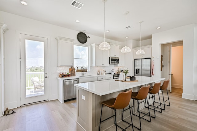 4101 5th St, Galveston, TX 77554 - kitchen with appliances with stainless steel finishes, a sink, light wood-style flooring, a kitchen island, and recessed lighting