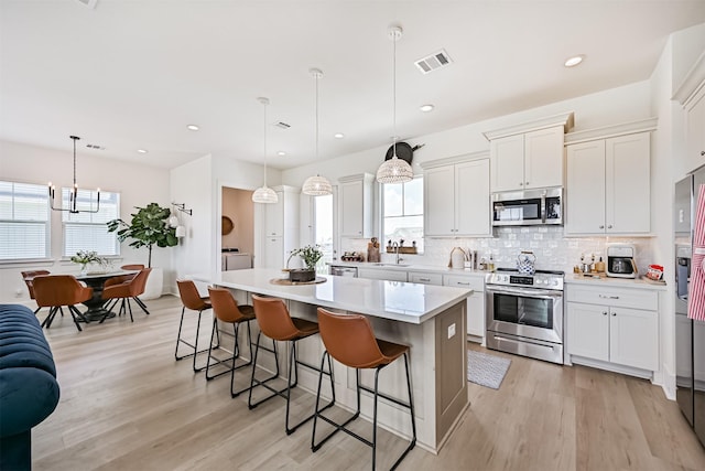 4101 5th St, Galveston, TX 77554 - kitchen with stainless steel appliances, a center island, a kitchen breakfast bar, light wood finished floors, and recessed lighting