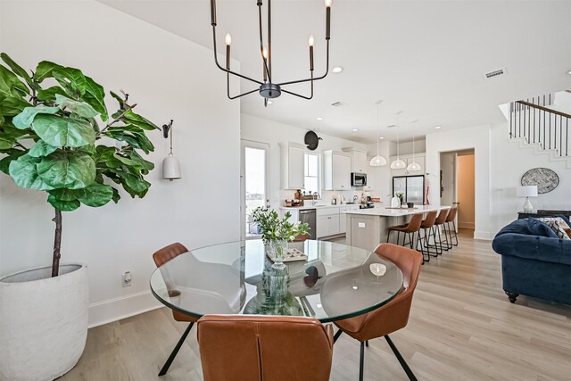 4101 5th St, Galveston, TX 77554 - dining room featuring light wood-style flooring, stairs, a chandelier, and baseboards
