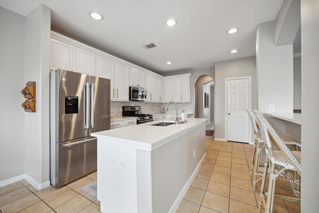 9110 Kinnel Ln, Tomball, TX 77375 - kitchen featuring stainless steel appliances, a sink, arched walkways, white cabinets, and light tile patterned floors