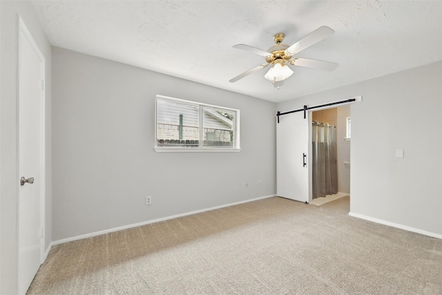 10119 Peachridge Dr, Houston, TX 77070 - unfurnished bedroom featuring light colored carpet, a barn door, baseboards, and a walk in closet