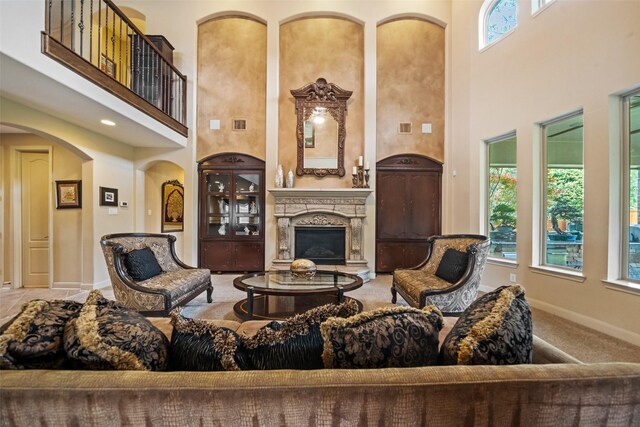 13803 Oak Fair Bnd, Cypress, TX 77429 - living room with a high ceiling, arched walkways, a glass covered fireplace, baseboards, and carpet