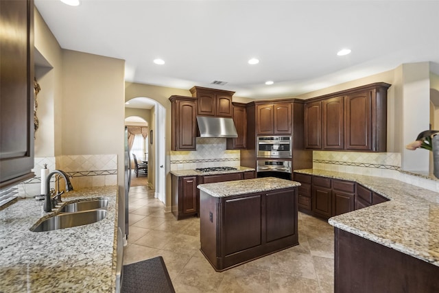 13803 Oak Fair Bnd, Cypress, TX 77429 - kitchen featuring under cabinet range hood, arched walkways, a sink, stainless steel appliances, and backsplash