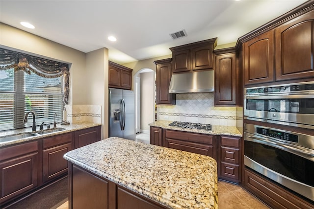 13803 Oak Fair Bnd, Cypress, TX 77429 - kitchen featuring stainless steel appliances, under cabinet range hood, a sink, arched walkways, and backsplash